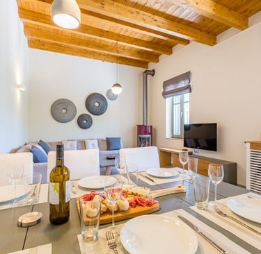 Rustic-chic living and dining room with wooden ceiling beams at Villa Skyphos