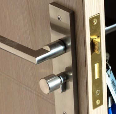 Close-up of a wooden residential door showing both inside/outside handles, with a key in the keyhole & a secure lock