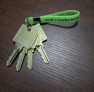 A Jack’s Locksmith green key ring with golden keys attached representing a master key lock system