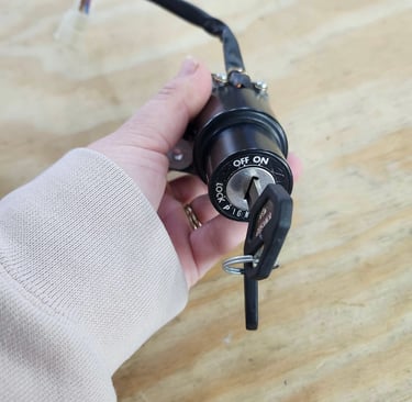 Hand holding a motorcycle ignition cylinder with key inserted