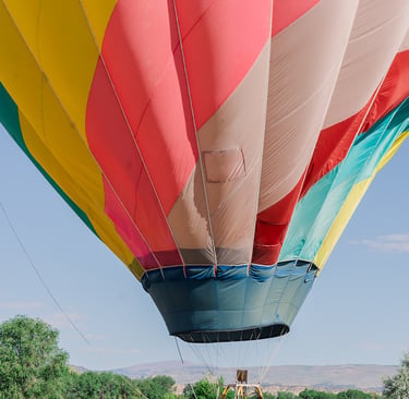 A group of people preparing a colorful hot air balloon for flight in a grassy field.