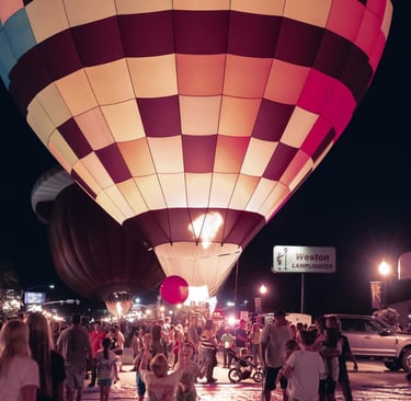 A glowing hot air balloon illuminates the crowd at the Dinah Soar Days Balloon Festival at night.