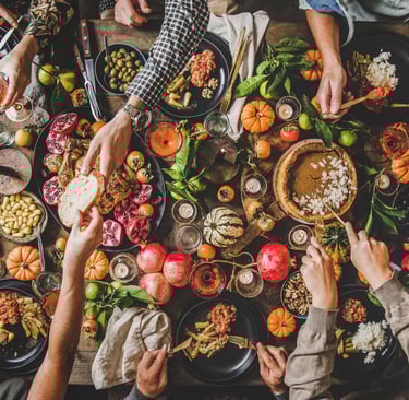 Many hands sharing an abundance of food at the table.
