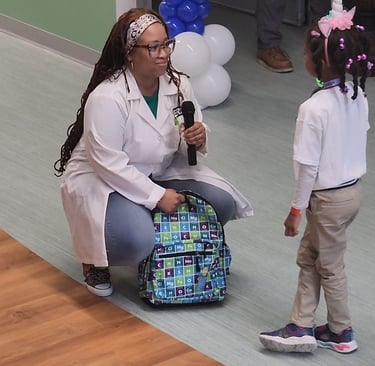 Shenell giving away a STEM themed book bag filled with her books to a child