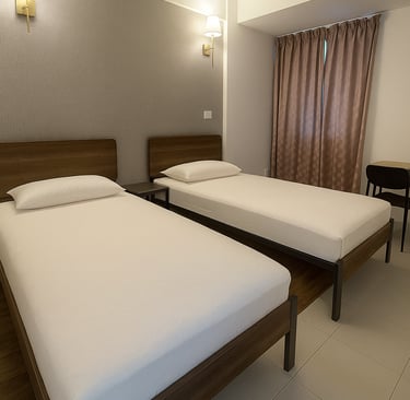 Modern hotel room featuring two twin beds with wooden frames and white linens under warm wall-mounted lamps.