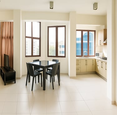 Modern open plan apartment with a dining set, kitchen cabinets, and bright windows.