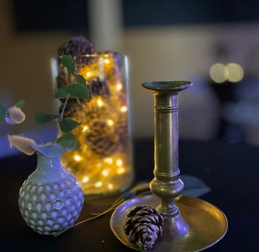 Composition décorative pour mange-debout avec bougeoir en laiton, vase texturé, eucalyptus, pommes d