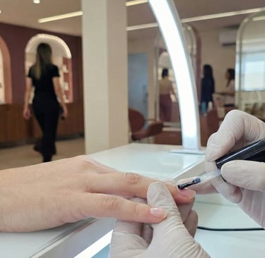 Manicure aplicando gel de blindagem para proteção e fortalecimento das unhas naturais.