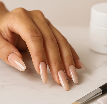 Close-up da mão esquerda de uma mulher com unhas alongadas impecáveis em formato amêndoa, com acabamento brilhante e tom nude