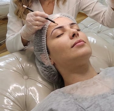 Designer realizando o mapeamento facial e design de sobrancelhas na maca do We Hall Beauty.