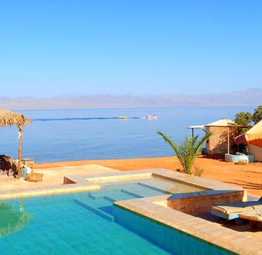 Swimmingpool am Strand mit vorbeifahrendem Boot im Meer