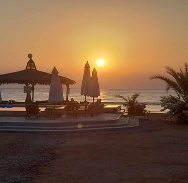 ein Sonnenaufgang an einem Strand mit Sonnenschirmen