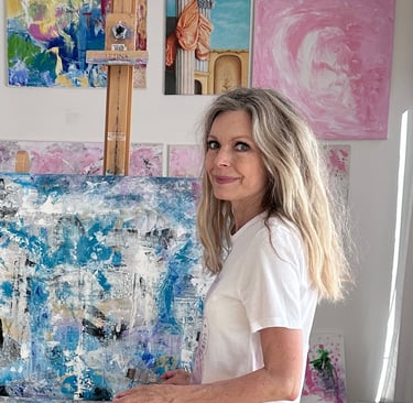 Artist Jeannie Berglund in her studio in front of a painting in teal, gold and white