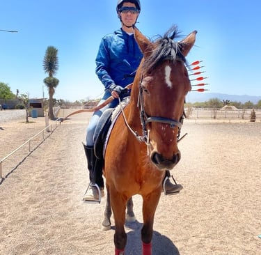 a man in a blue jacket riding a horse witn bow and arrows