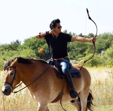 a man is riding a horse with a bow and arrows. equestrian archery