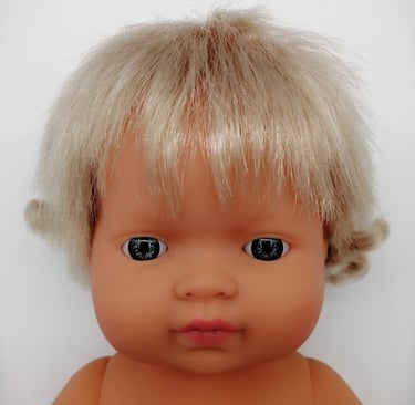 a Miniland baby doll with blonde hair and blue eyes