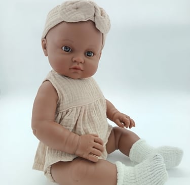 Minikane toddler doll in sitting position dressed in beige outfit