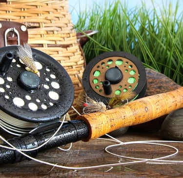 Fly fishing gear with a cork handle rod, reels, and flies next to a woven wicker creel basket.
