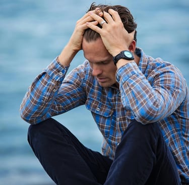 a man sitting on a bench with his hands on his head