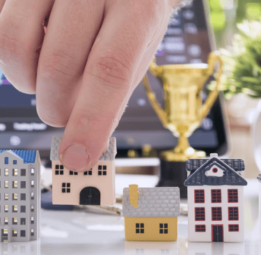 a person's hand is placing a house model of a house
