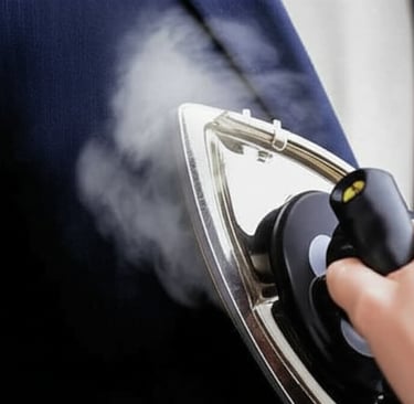 An iron steaming a dark blue suit jacket.