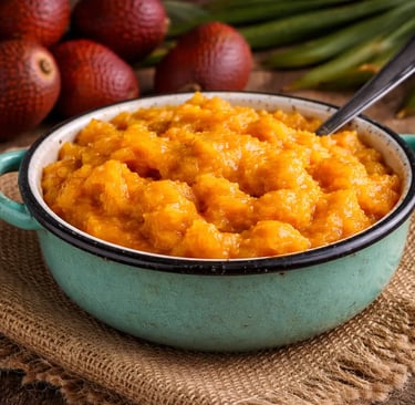 Polpa de buriti amassada servida em uma tigela de cerâmica azul, com frutos inteiros de buriti ao fu