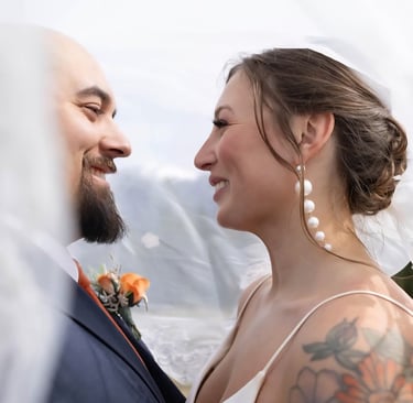 a bride and groom standing in front of a veil
