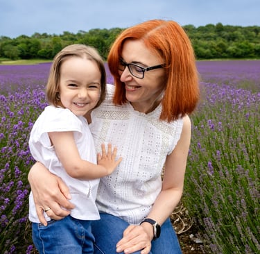 A smiling mother and daughter hugging in a vibrant purple lavender field during summer.