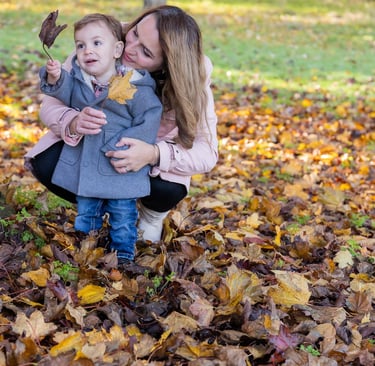a woman and her baby looking at a leave in a park
