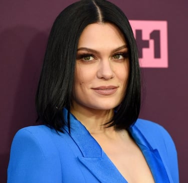 Jessie J com cabelo curto e preto, posando com um blazer azul.