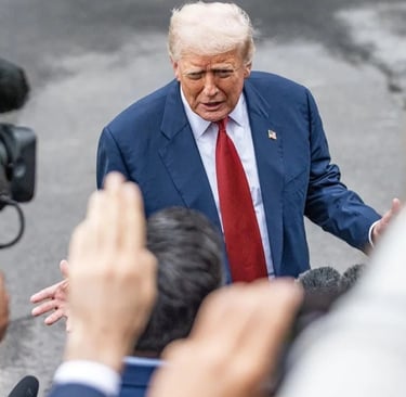 Donald Trump, com terno azul e gravata vermelha, em meio a repórteres e câmeras.