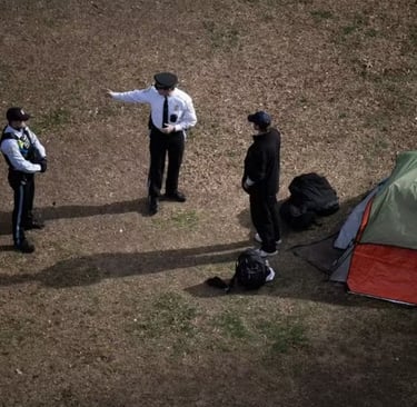  Visão aérea de policiais interagindo com pessoas ao lado de uma barraca em um gramado.