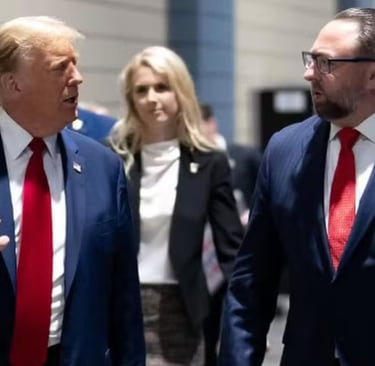 Donald Trump caminha e conversa com um homem de terno, com outras pessoas ao fundo.
