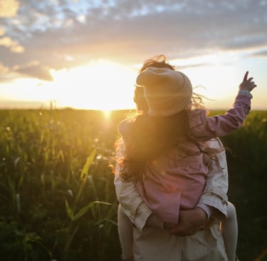 a woman holding a child in a field