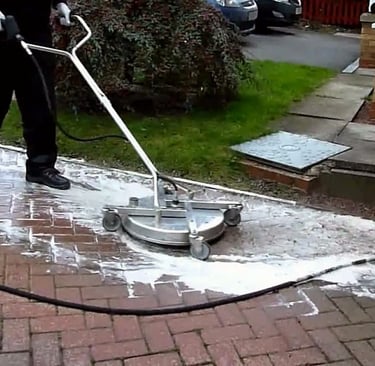 A man using a surface cleaner to clean a brick paver path