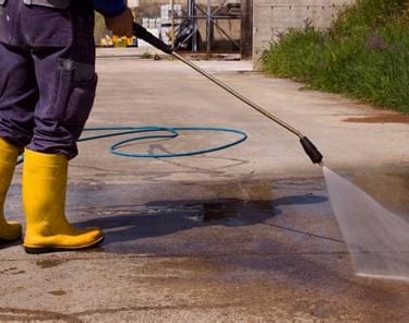 Pressure washing services worker pressure washing a dirty sidewalk