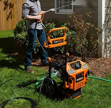 man using a pressure washer to clean a house