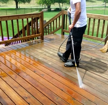 A man cleaning a wooden deck with a pressure washer