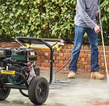 man cleaning a patio area with a pressure washer