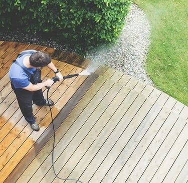 man cleaning a wooden deck with a pressure washing unit