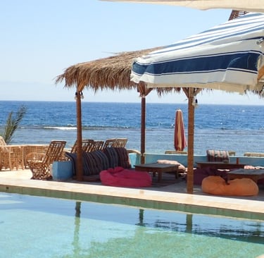 Beach view with lounge area between swimming pool and the sea