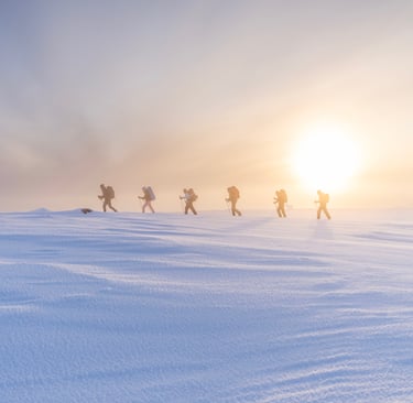 a group of people walking across a snow covered ground