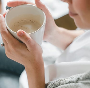 Artimas kadras moters, laikančios rankose kavos puodelį. Simbolizuojant laiko skyrimą sau.