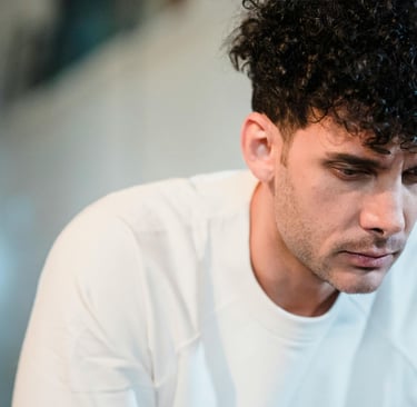 Tamsiaplaukis vyras susirūpinusiu veidu, esantis šviesiame kambaryje