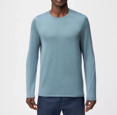 a man in a blue sweater and jeans standing in front of a white background