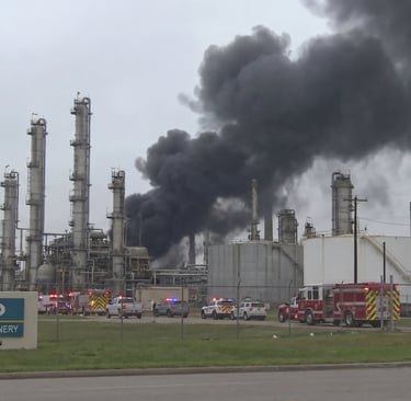 Black smoke billows from the Valero Three Rivers Refinery as fire trucks and emergency vehicles respond.