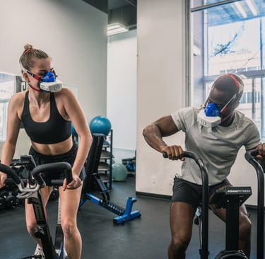 a man and woman in masks in a gym taking a VO2MAX test