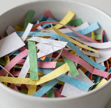 Close-up of a child's hands exploring a bin of soft cotton balls and feathers.
