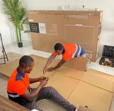 Two professional movers in orange high-visibility vests with reflective stripes carefully measure an