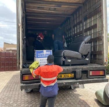A professional mover in an orange high-visibility vest with reflective strips and blue pants, holdin